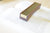 A rectangular wooden book weight with a brass center block, resting on an open book.