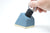 Blue concrete pen holder with brass shown with foam inside being removed with a tool by a hand