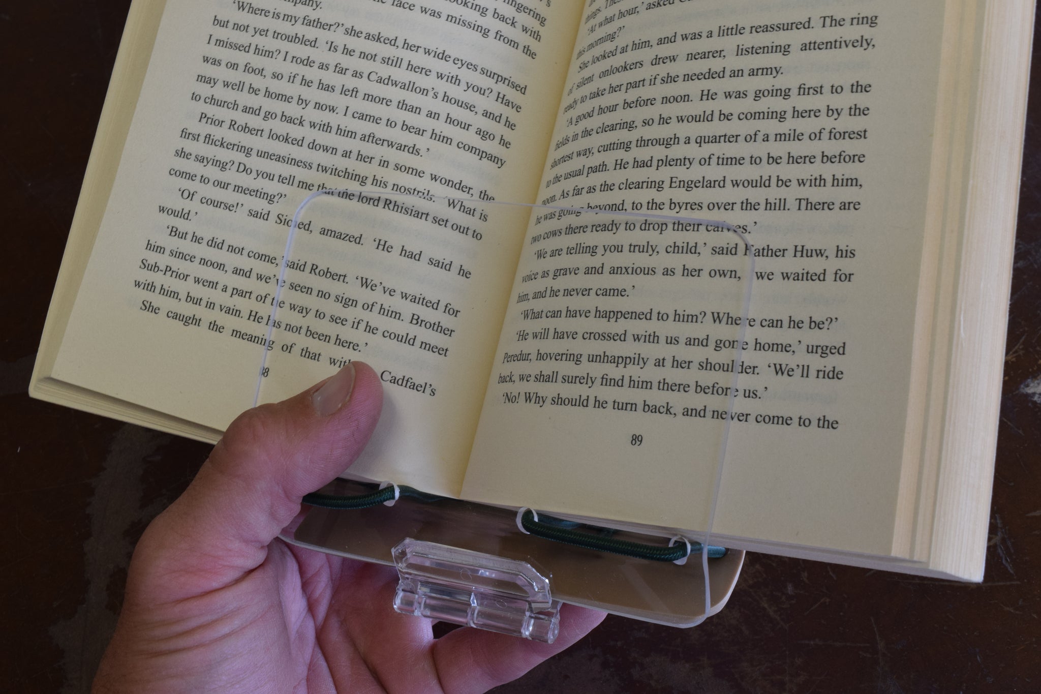 A book clip with a book in it being held by a hand