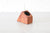 Wooden wedge pen holder on a light gray surface with a white brick wall background