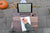 Looking down on someone writing in a notebook with a fountain pen on a wood lap desk holding a tablet